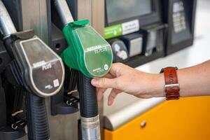 Man holding a gasoline nozzle in his hand on self-service filling station in Europe photo