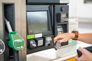 cerca arriba ver de hombre mano paga para combustible con un crédito tarjeta en terminal de autoservicio relleno estación en Europa foto