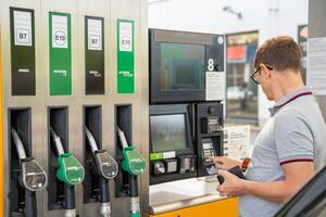 el hombre paga para combustible con un crédito tarjeta en terminal de autoservicio relleno estación en Europa. alto calidad foto