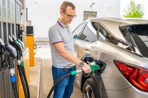 el conductor llena arriba costoso gasolina en autoservicio relleno estación en Europa foto