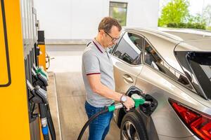 el conductor llena arriba costoso gasolina en autoservicio relleno estación en Europa foto