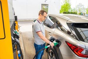 el conductor llena arriba costoso gasolina en autoservicio relleno estación en Europa. alto calidad foto