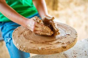 Close up view of potter hands, teen makes ceramic pot on a potter's circle . High quality photo