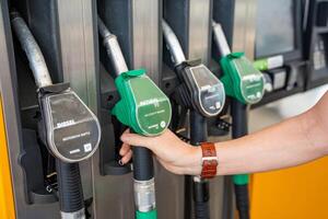 hombre participación un gasolina boquilla en su mano en autoservicio relleno estación en Europa. alto calidad foto