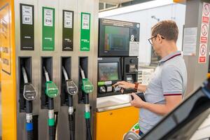 Praga, checa república - abril 12, 2024. el hombre paga para combustible con un crédito tarjeta en terminal de autoservicio relleno estación en Europa. alto calidad foto