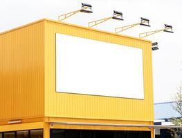 Mock up white background billboard on yellow building with spotlight. Clipping path for mockup photo