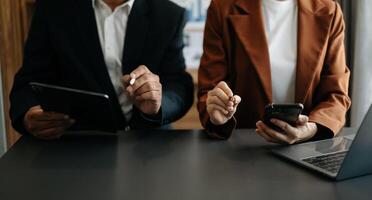 Business documents on office table with smart phone and calculator digital tablet and graph business with social network diagram and two colleagues discussing data photo