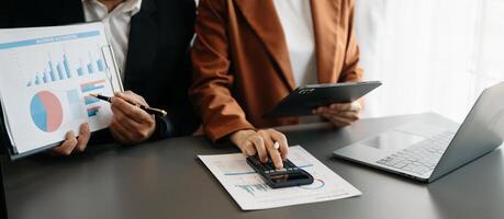 Business documents on office table with smart phone and calculator digital tablet and graph business with social network diagram and two colleagues discussing data photo