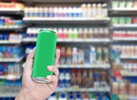 Hand hold mockup green aluminum can with many drinks on shelf background photo