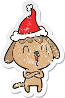 mignonne main tiré affligé autocollant dessin animé de une chien portant Père Noël chapeau png