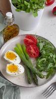 Fresco primavera ensalada con hervido huevos, espárragos, y Tomates en un brillante día video
