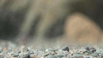 A blurry image of a rock with a blurry background. The rock is surrounded by a lot of small rocks, giving the impression of a rocky beach. The image has a sense of depth and texture. video