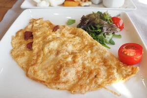 llanura huevo tortilla servido con Fresco ensalada en mesa foto