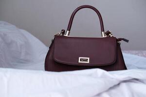 empty fashion leather handbag on bed, close up photo