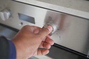 Close up of men hand setting temperature control on oven. photo