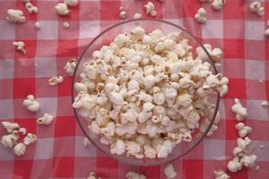 A wooden bowl of salted popcorn at table. photo