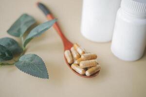 herbal medicine capsule on a wooden spoon photo