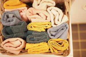 A storage basket made of wood filled with an assortment of towels photo