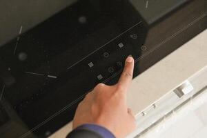 man hand turning on the ceramic black induction stove photo