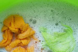 washing s clothes in a green bowl with water photo