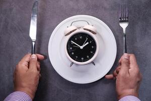 Alarm clock on plate on wooden table, top view. photo