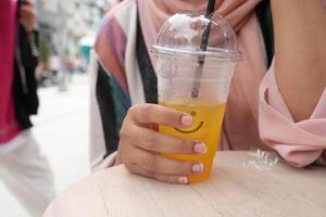 naranja jugo con hielo cubo en un el plastico envase foto