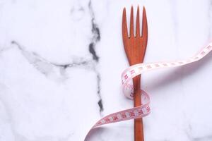 wooden fork and measurement tape on table. photo