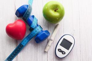 blood sugar measurement kits, dumbbell and apple on table photo