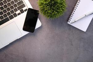 top view of smart phone, laptop and notepad on table photo