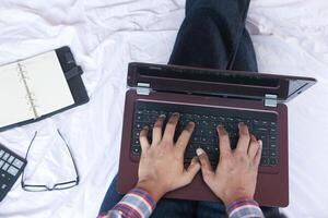 young man working on laptop at home on bed photo