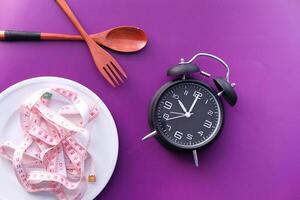 Diet concept, Measuring tape in empty plate with spoon and fork photo
