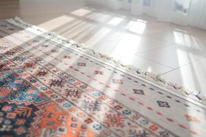 A patterned rug rests on the flooring beside a mirror photo