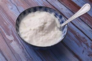 close up of fresh yogurt in a bowl on color background photo