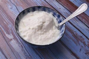 close up of fresh yogurt in a bowl on color background photo