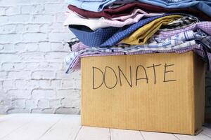 Donation box with donation clothes on a wooden table . photo