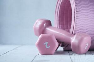 Close up of pink color dumbbell and exercise mat on table photo