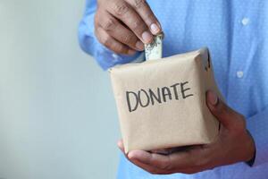 Man puts donation in a box with copy space . photo