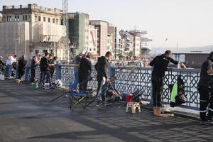 Turkey istanbul 12 january 2024. Fishermen fishing with fishing rods from the Galata Bridge photo