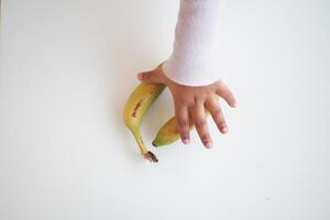 top view of child hand reaching for a banana photo