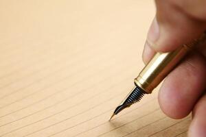 man's hand writing with a fountain pen on paper photo