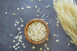 avena copos en un un de madera cuenco en negro antecedentes foto