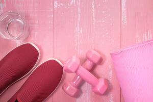 Close up of pink color dumbbell and glass of water on table photo