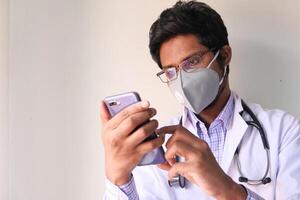 Doctor in face mask using smartphone in the hospital. photo