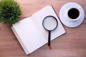 open book and magnifying glass on table. photo