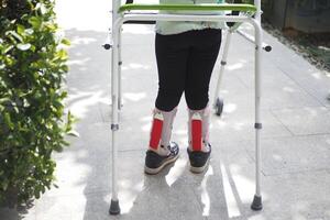 child with walking frame and knee orthosis outdoor photo