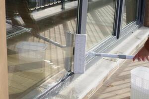 Rubber squeegee cleans a soaped window. photo