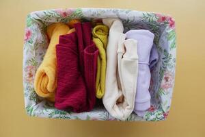 A rectangle violet basket of kid cloths on the table photo