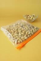 pistachios nuts in a plastic bag on color background photo