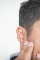 young man having ear pain touching his painful ear , photo