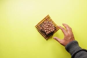 hand reaching for candy with mixed nut on yellow background photo